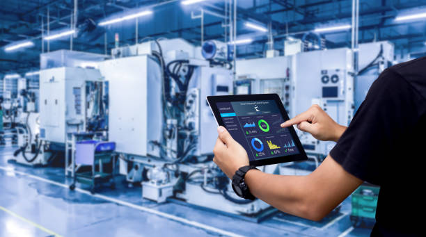 A Person Holding a Tablet With Machines in the Background