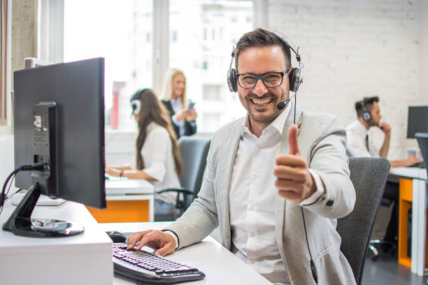 Man in Front of Computer with Headset on showing Thumbs Up
