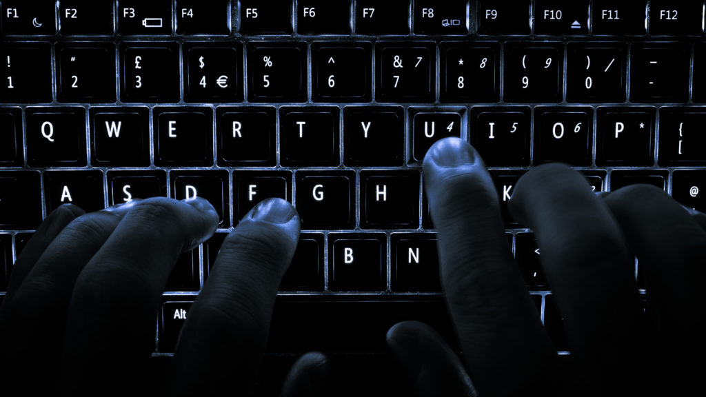 Human Hand Typing on a Backlit Keyboard