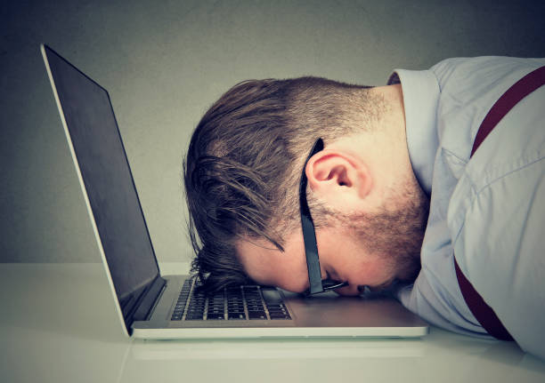 Man Looking Exhausted Lying on top of Laptop